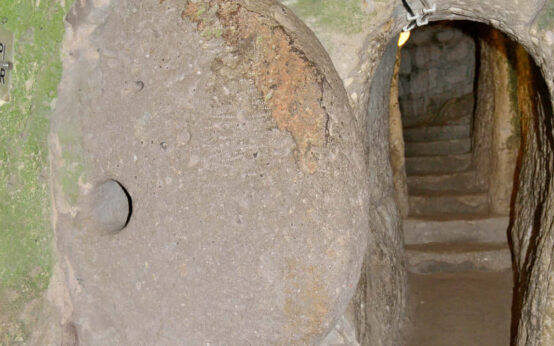 Tunnel scavato nel tufo con una grande porta circolare di pietra nella città sotterranea di Derinkuyu