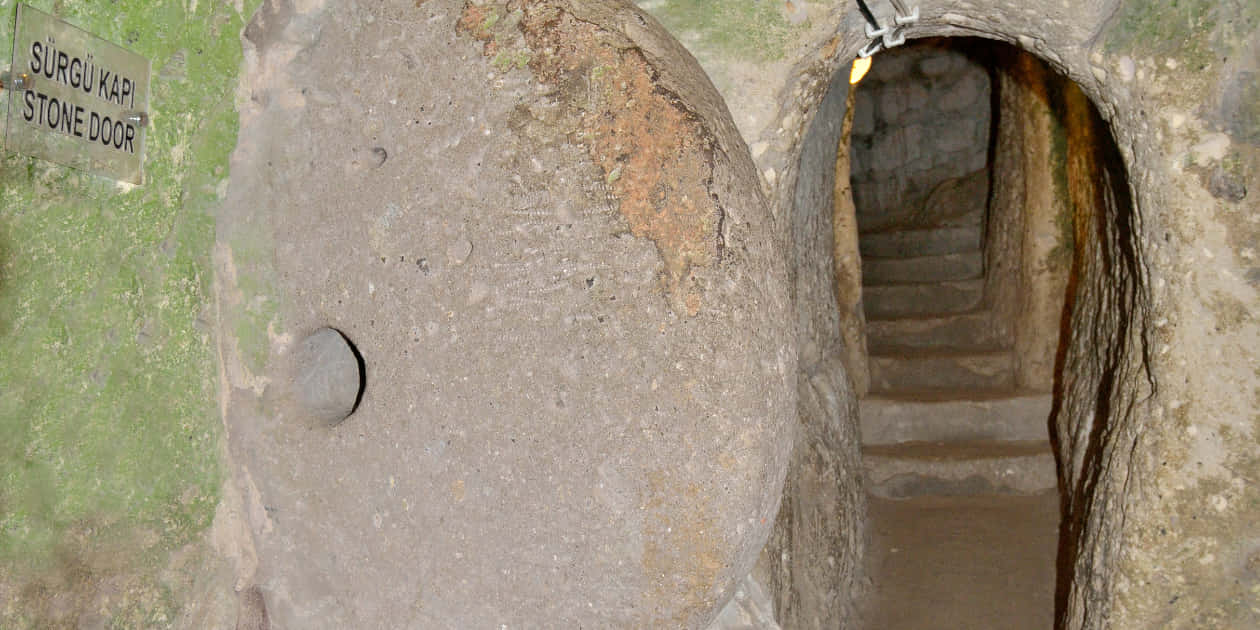 Tunnel scavato nel tufo con una grande porta circolare di pietra nella città sotterranea di Derinkuyu