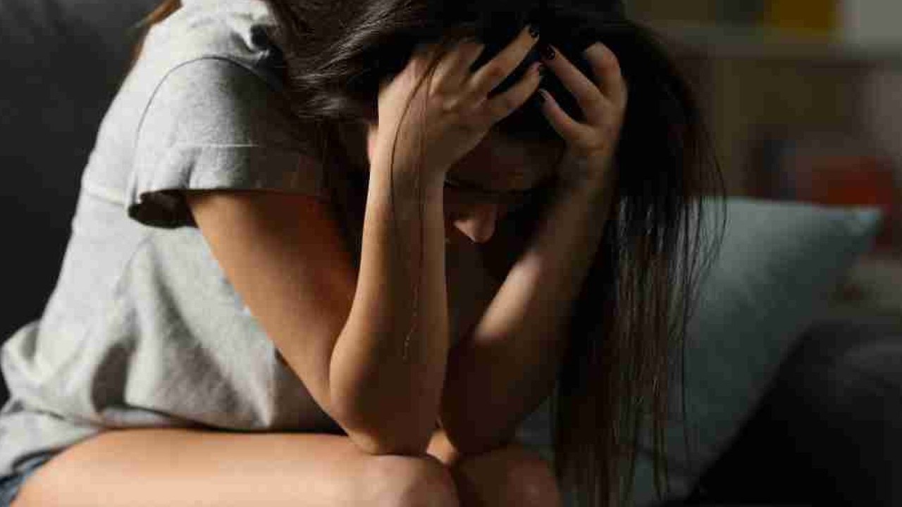 Persona in lutto seduta da sola, espressione di dolore e stress fisico