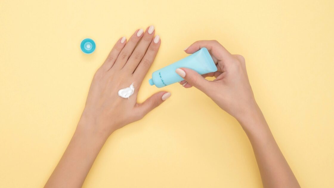 Applicazione di crema idratante sul dorso della mano per proteggere mani screpolate e unghie fragili col freddo