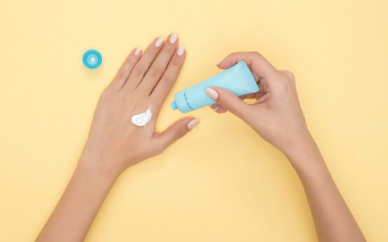 Applicazione di crema idratante sul dorso della mano per proteggere mani screpolate e unghie fragili col freddo