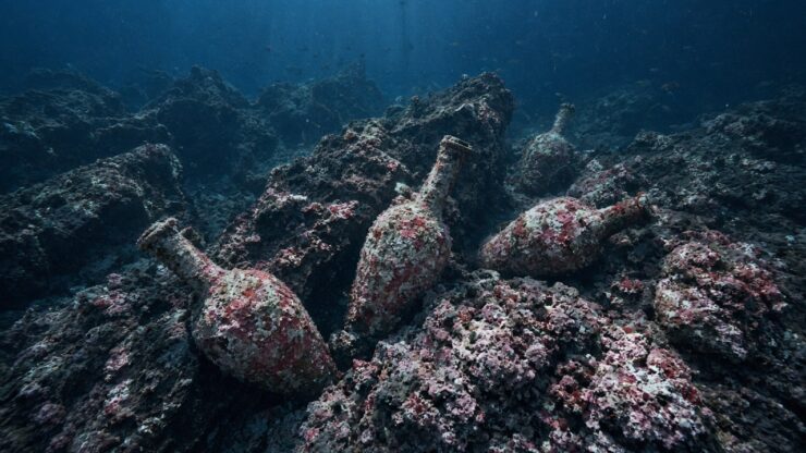 Illustrazione generata con AI: anfore romane ricoperte di concrezioni rosa incastrate tra le rocce di un fondale marino profondo